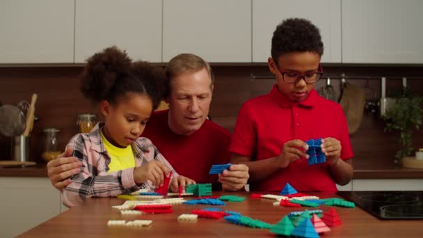 Grandfather and multiracial grandchildren playing developing game at home — Stockvideo
