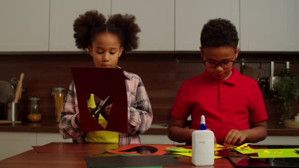 Engrossed schattige schooltijd zwarte kinderen het maken van handgemaakte cadeau van gekleurd papier — Stockvideo