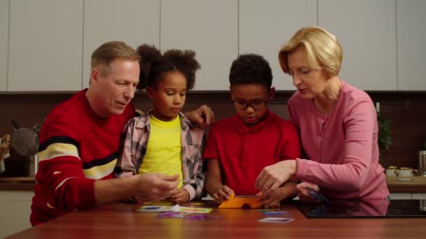 Petits-enfants multiethniques excités avec des grands-parents jouant puzzle de couleur à l'intérieur — Video