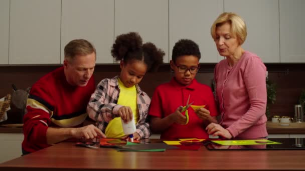 Πολυεθνική πολυφυλετική οικογένεια με παιδιά να κάνουν απλικέ από χρωματιστό χαρτί — Αρχείο Βίντεο