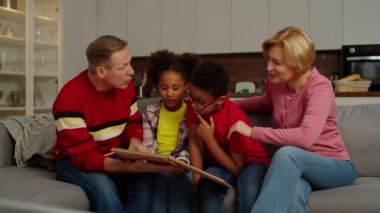 Büyükannesi ve büyükbabası eski aile fotoğraflarına bakan çok kültürlü çocuklar.