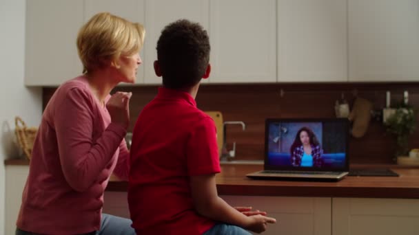 Hátsó nézet a nagymama és a többnemzetiségű fiú, hogy az online videohívás otthon — Stock videók