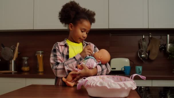 Cute usia sekolah Afrika Amerika gadis bermain ibu dengan boneka di dalam ruangan — Stok Video