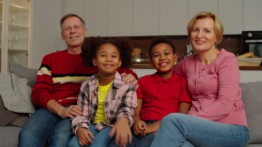 Çoklu etnik çeşitlilikte birleşmiş bir ailenin portresi. Çocuklar içeride gülümsüyor.
