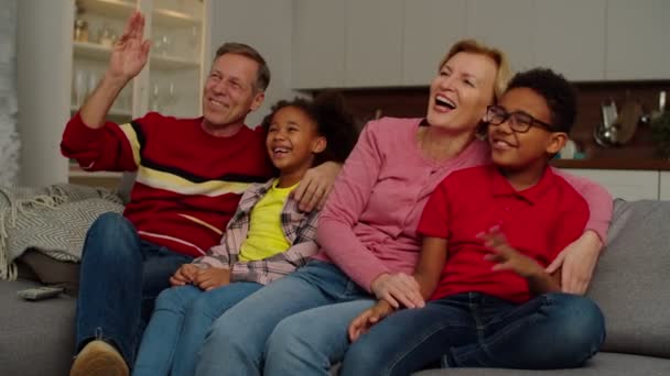 Carefree grandparents and joyful multiethnic children watching comedy show on tv — Stockvideo