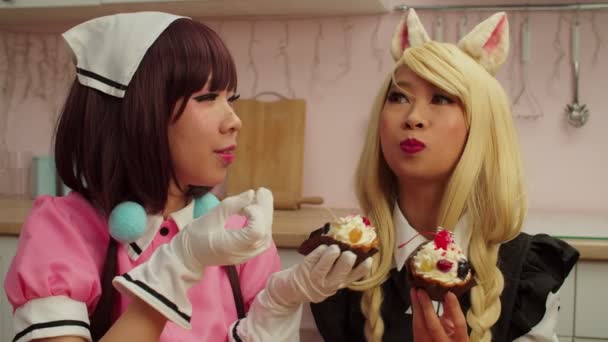 Adorável asiática cosplayers do sexo feminino partilha e degustação deliciosos cupcakes dentro de casa — Vídeo de Stock