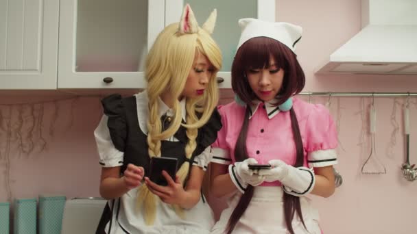 Positive pretty Asian women in anime cosplay costume web surfing on cellphones — Stock Video