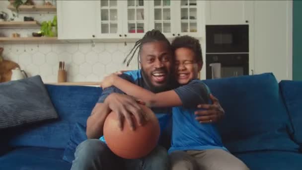 Överlycklig afrikansk far och pojke tittar på tv och hejar basketmatch — Stockvideo