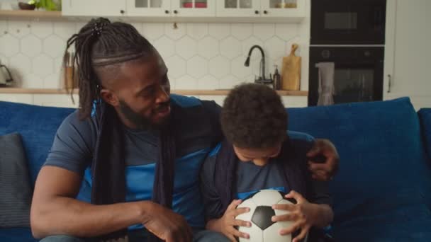 Pečující africký otec povzbuzující rozrušený syn s fotbalovým míčem po týmové porážce — Stock video