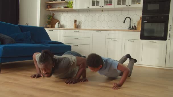 Aktif Afrikalı Amerikalı baba ve tatlı oğlu evde şınav çekiyorlar. — Stok video