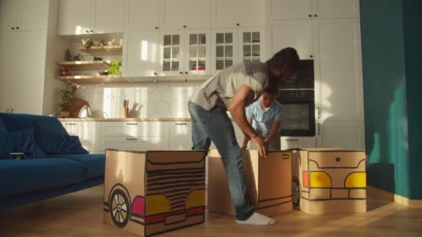 Netter afroamerikanischer Sohn und Vater bastelt Spielzeugauto aus Pappe zu Hause — Stockvideo