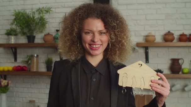 Весела прекрасна жінка агент з нерухомості тримає ключ будинку і домашню модель — стокове відео