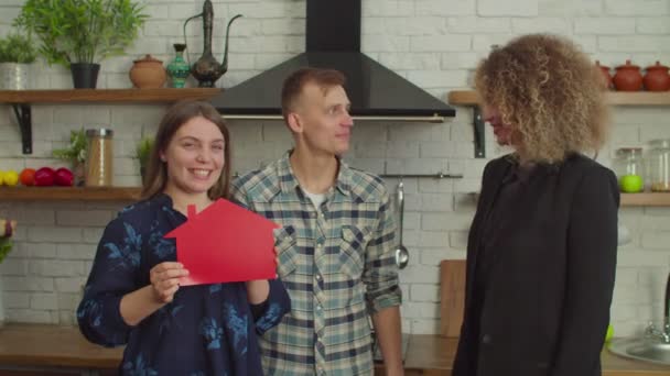 Радостная пара домовладельцев, получающих ключи от дома от женщины-риэлтора в помещении — стоковое видео