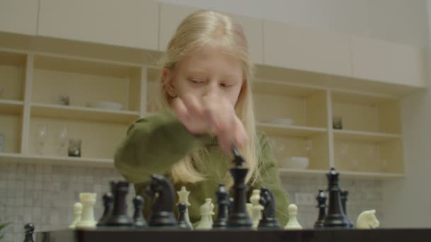 Продумана мила дівчина шкільного віку з втратою слуху грає в шахи в приміщенні — стокове відео