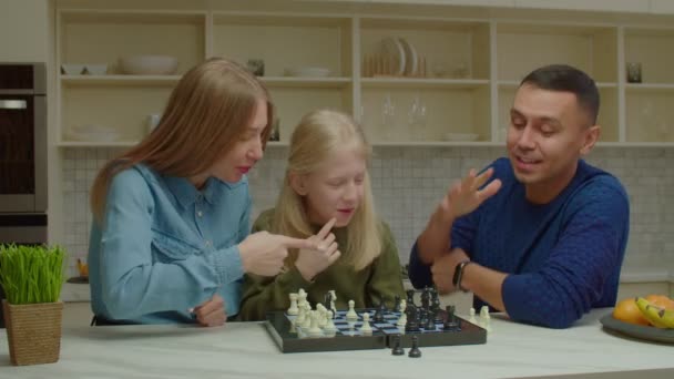 Vreugdevol slechthorend gezin en jong meisje dat thuis schaakspel speelt — Stockvideo