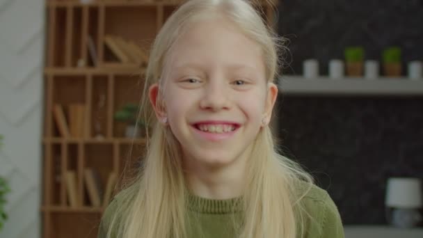 Портрет беззаботной девочки младшего возраста с потерей слуха, смеющейся в помещении — стоковое видео