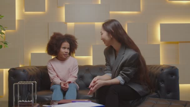 Gondoskodó ázsiai női pszichológus dolgozik imádnivaló ideges kis afrikai lány — Stock videók