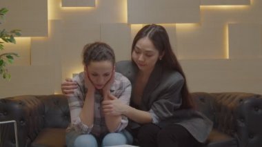 Asyalı kadın psikolog psikoterapi sırasında depresyondaki kadın hastayı teselli ediyor.