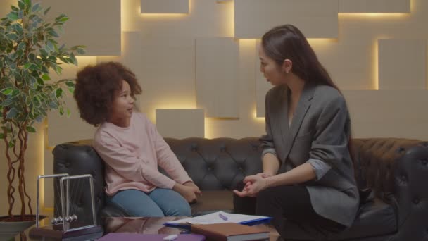 El cuidado de la mujer asiática trabajador social que trabaja con la edad escolar negro problema niño — Vídeo de stock