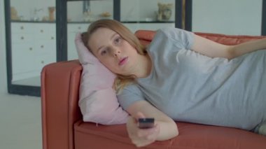 Sıkıcı orta yaşlı bir kadının portresi kanepede uzanıyor, uzaktan kumandayla televizyon kanallarını değiştiriyor, hafta sonu evde dinlenirken ve televizyon izlerken olumsuz duygular ifade ediyor..