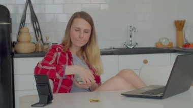 Gündelik giysiler içindeki olgun bir kadın mutfak masasında oturuyor, gününü ve geleceğini tahmin ediyor, tarot kartı okuyor ve evdeki mutfaktaki dizüstü bilgisayarını kullanarak kartların anlamını kontrol ediyor..