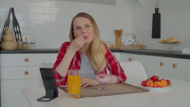 여성을 식사를 아침에 부엌에서 휴식을 취하면서 신선하게 딸기와 맛있는 요구르트를 — 비디오
