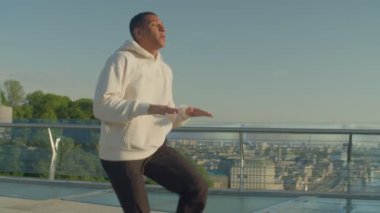 Aktif sağlıklı yaşam tarzı çekici Afrikalı erkek koşucu spor kıyafetleriyle ısınıyor, tek koluyla egzersiz yapıyor şafak vakti dışarıda antrenman yapmadan önce..