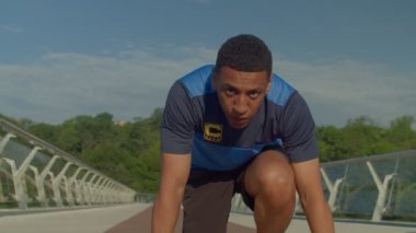 Formalı konsantre motive olmuş yakışıklı zenci koşucunun portresi başlangıç pozisyonunda duruyor, yarış pistinde koşmaya hazırlanıyor ve gün doğumunda dışarıda spor antrenmanı yapıyor..