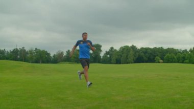 Etkin motivasyonlu Afrikalı erkek futbol oyuncusu spor formasında çeviklik tatbikatları, hız ve hızın artırılması, külahlara kadar koşma ve dışarıda yeşil alan üzerindeki egzersizleri kesme..