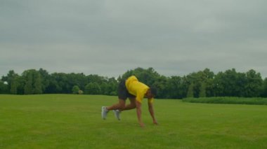 Spor kıyafetleri içinde aktif, sağlıklı yaşam tarzı yakışıklı Afro-Amerikan erkek. Burpee egzersizi yapıyor, vücut kaslarını güçlendiriyor. Kamu parkında egzersiz yaparken kalp atış hızını ve kan akışını artırıyor.