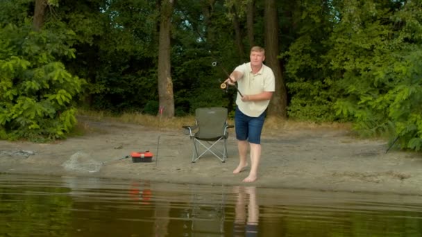 잘생긴 어부는 활동을 즐기고 낚시를 즐기며 시골에서 휴가를 보내는 연못에 — 비디오