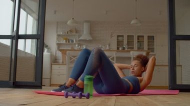 Çekicilik, spor yaparken karın kasları çalıştıran, karın kaslarını ve karın kaslarını güçlendiren, kasların hareketliliğini ve esnekliğini artıran aktif giyimli siyahi bir kadına uygun..
