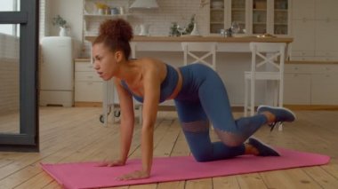 Azimli, oldukça sportif, formda, spor yapan, yoga yapan, itfaiye musluğu egzersizi yapan, iç mekanda antreman yaparken kalça ve vücut kaslarını güçlendiren Afro-Amerikan kadın..