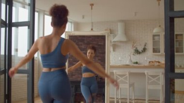 Zayıf gülümseyen Afrikalı kadın spor kıyafetleriyle vücut şekline bakıyor, diyet planının ve kilo verme başarısının sevinçli başarısı, neşeli ruh hali ve mutluluğu ifade ediyor.