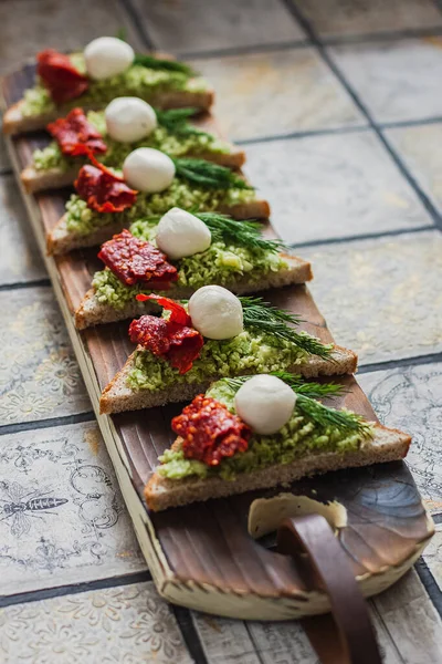 Mini üçgen kanepeler avokado, mozarella ve kurutulmuş domatesli bruschetta.