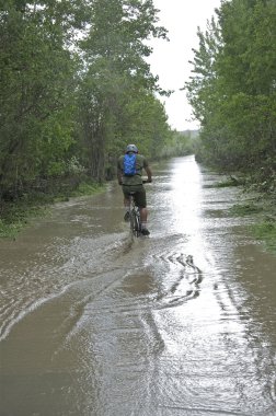 Cyclists enters pathway under water due to flooding clipart
