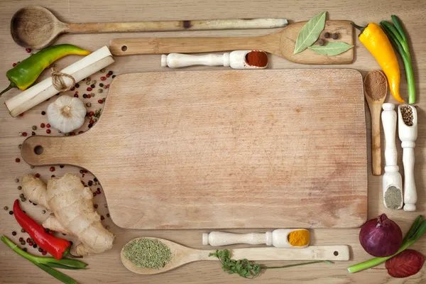 Vegetables and spices border and empty cutting board — Stock Photo, Image