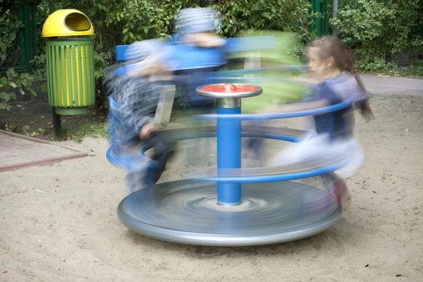Carousel in motion and happy kids on playground — Stock Photo, Image