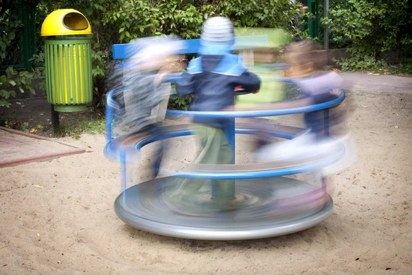 Carousel in motion and happy kids on playground — Stock Photo, Image