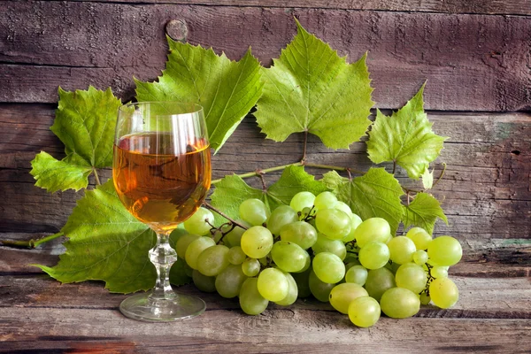 Glass of wine and grapes on old wooden boards — Stock Photo, Image