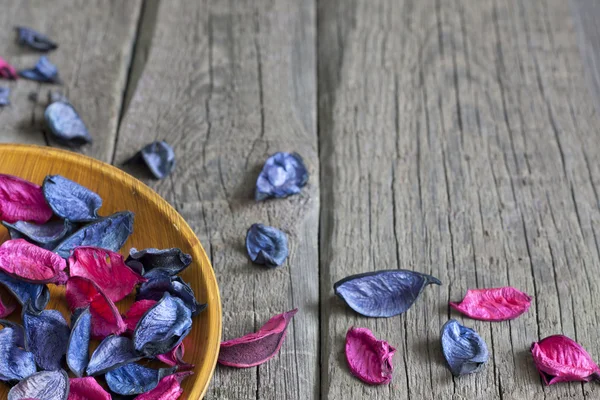 Dried petals in bowl on wooden boards spa concept background — Stock Photo, Image