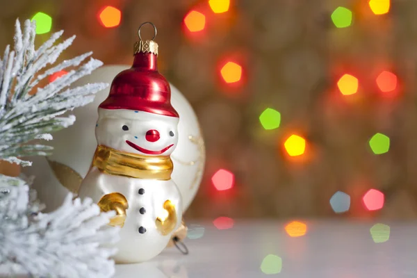 Snowman and baubles against blurred colorful background — Stock Photo, Image