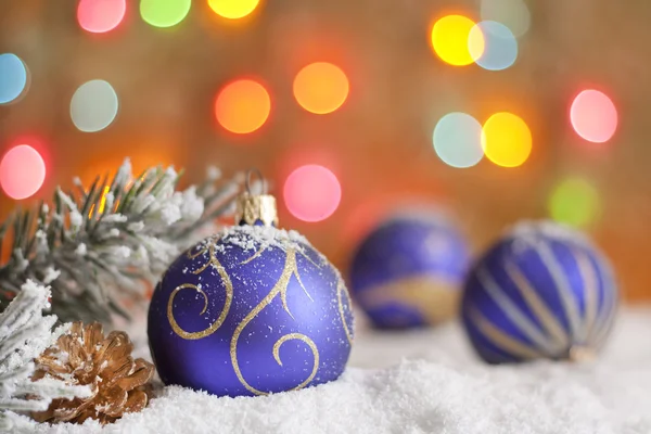 Christbaumkugeln auf Schnee vor verschwommenem buntem Hintergrund — Stockfoto