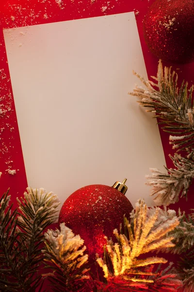 Hoja de papel y adornos navideños sobre fondo rojo Imagen De Stock