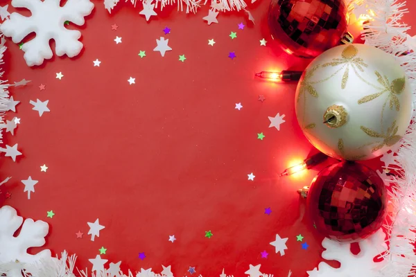 Luces navideñas bordean con adornos y nieve sobre fondo rojo — Foto de Stock