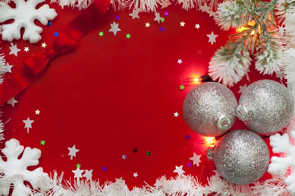 Luces navideñas bordean con adornos y nieve sobre fondo rojo —  Fotos de Stock