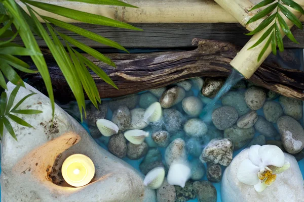 Caída de agua sobre piedras concepto de spa fondo con orquídeas y bambú — Foto de Stock