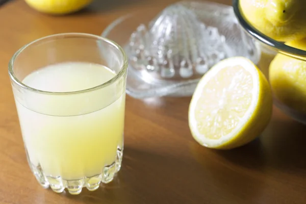 Succo di limone fresco con spremiagrumi sul tavolo — Foto Stock