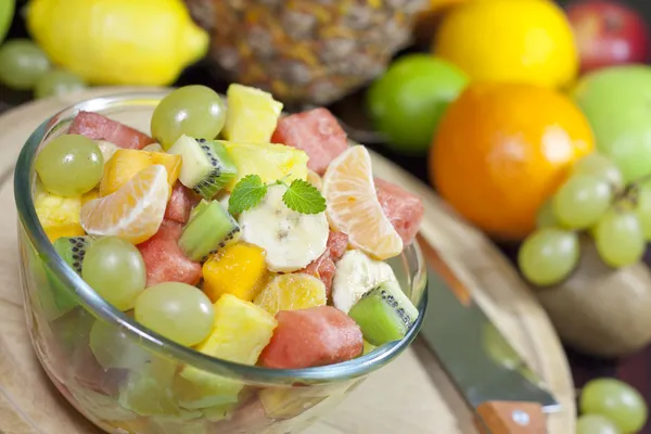 Fresh fruits salad in bowl in kitchen closeup — Stock Photo, Image