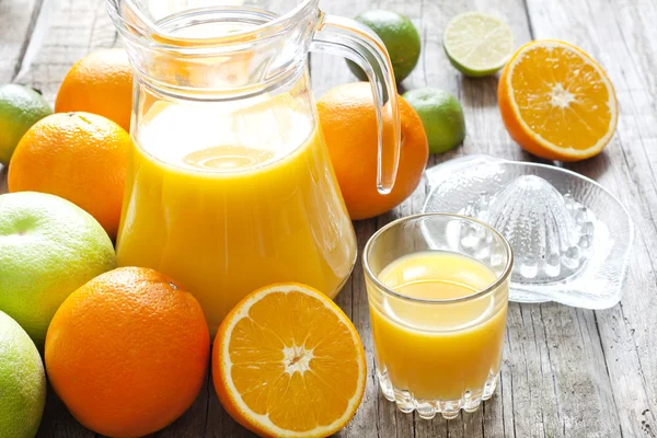 Zumo de naranja con pomelo de lima y exprimidor sobre tablas de madera —  Fotos de Stock